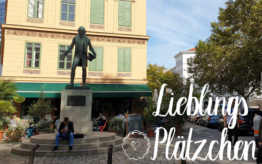 nestroy-statue vor einem gelben haus, im vordergrund der "lieblings-plätzchen"-schriftzug